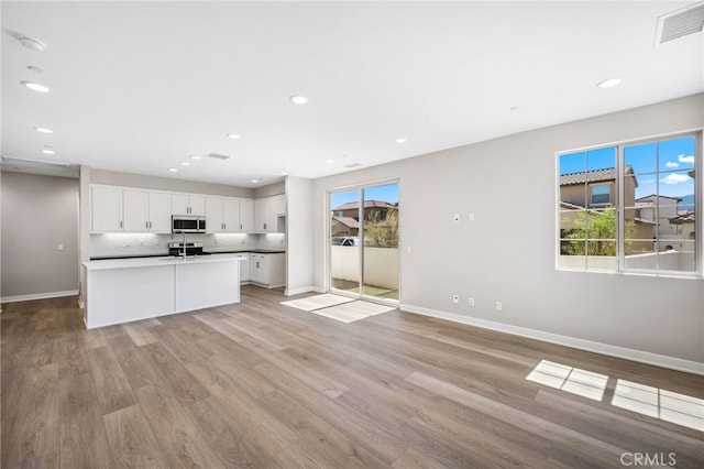 kitchen with light hardwood / wood-style flooring, appliances with stainless steel finishes, a wealth of natural light, and white cabinets