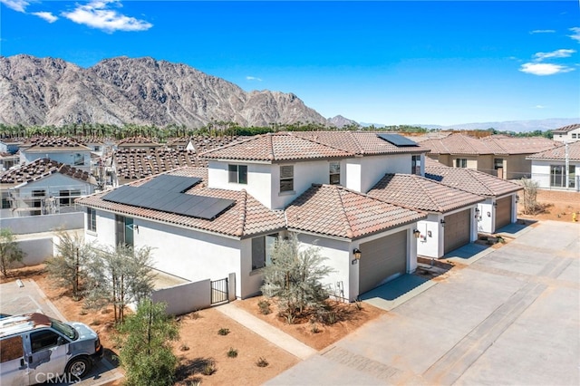 mediterranean / spanish home featuring solar panels, a mountain view, and a garage