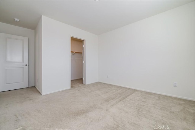 unfurnished bedroom featuring a walk in closet, light carpet, and a closet