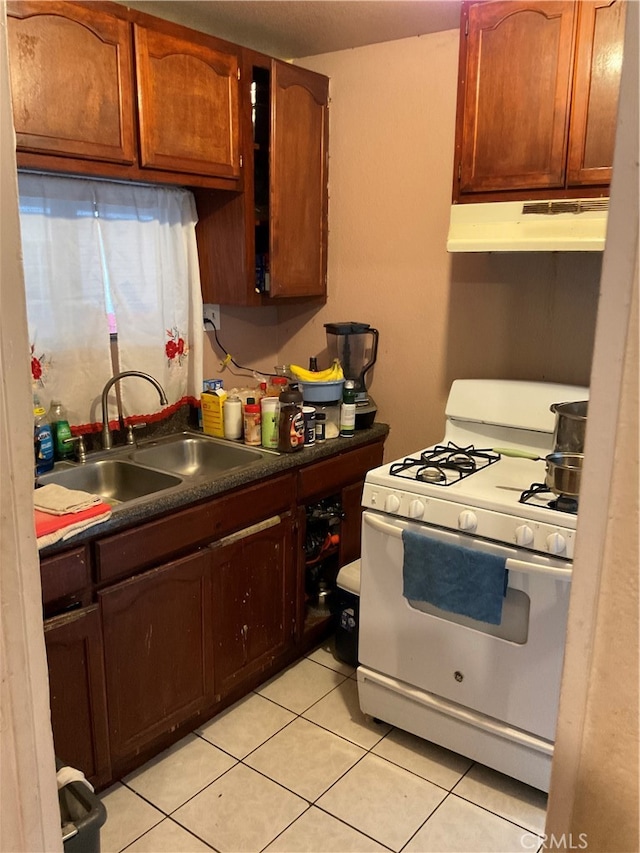 kitchen featuring white range with gas stovetop, sink, and light tile patterned floors