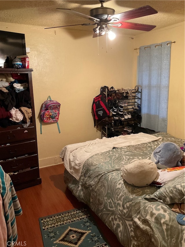 bedroom with ceiling fan, a textured ceiling, and dark hardwood / wood-style flooring