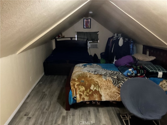 bedroom featuring hardwood / wood-style flooring, a textured ceiling, and vaulted ceiling