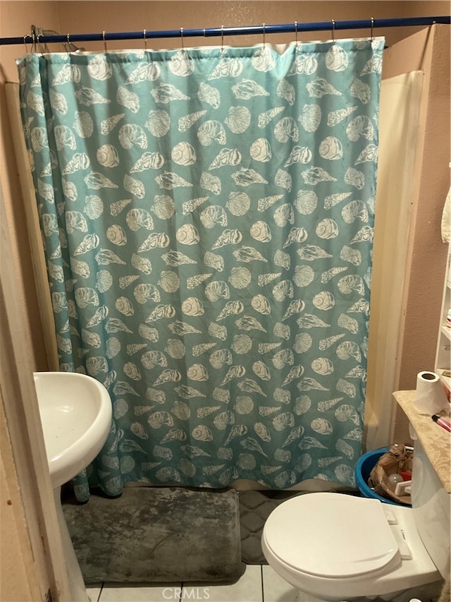 bathroom featuring sink, toilet, and tile patterned flooring