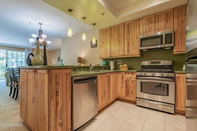 kitchen with kitchen peninsula, sink, decorative light fixtures, an inviting chandelier, and appliances with stainless steel finishes