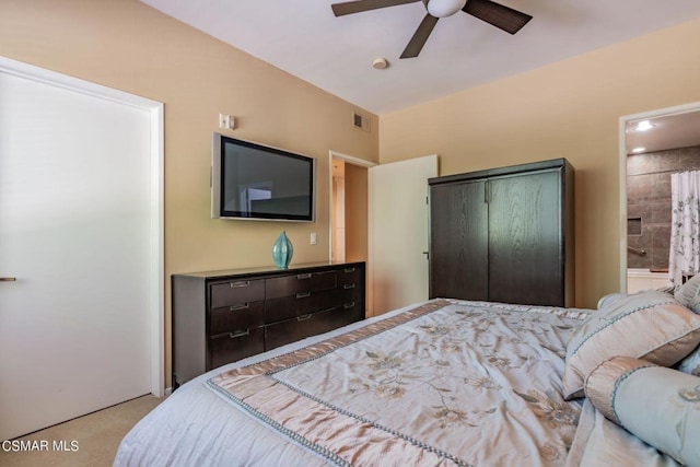 bedroom featuring light carpet, ensuite bathroom, and ceiling fan