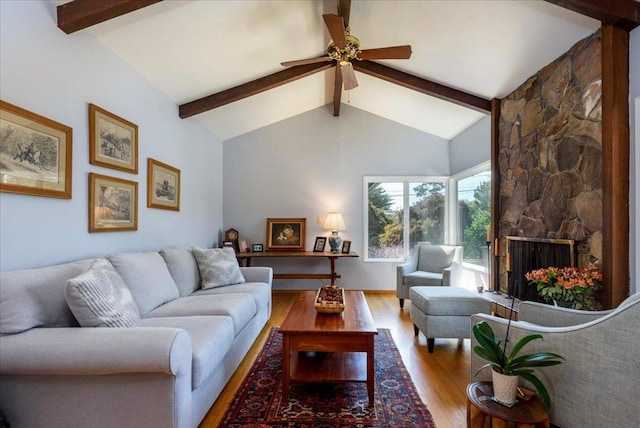 living room with ceiling fan, a fireplace, lofted ceiling with beams, and light hardwood / wood-style flooring