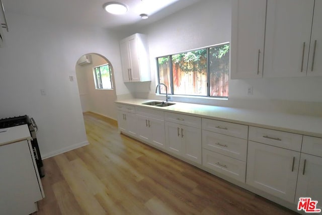 kitchen featuring sink, white cabinetry, light hardwood / wood-style floors, and white range oven