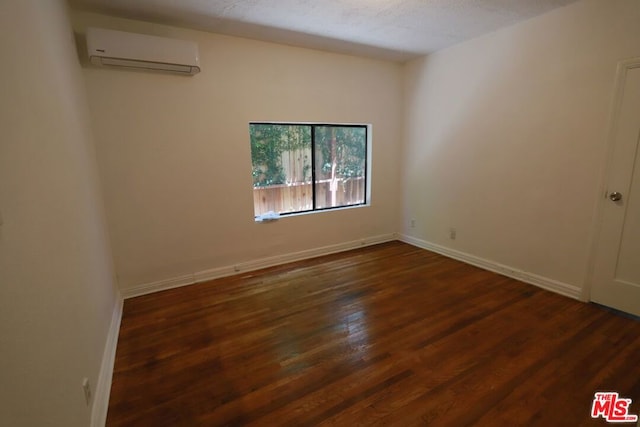 spare room with a textured ceiling, a wall mounted AC, and dark hardwood / wood-style flooring