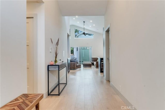 hall featuring light wood-type flooring and high vaulted ceiling