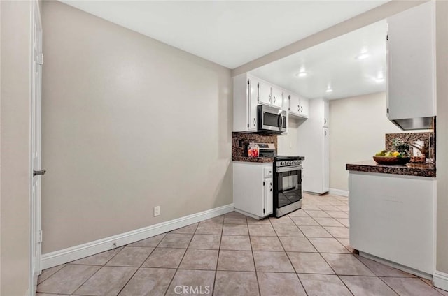 kitchen with appliances with stainless steel finishes, white cabinets, light tile patterned flooring, and decorative backsplash