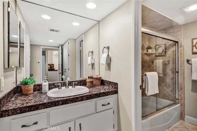 bathroom featuring tile patterned flooring, bath / shower combo with glass door, and vanity