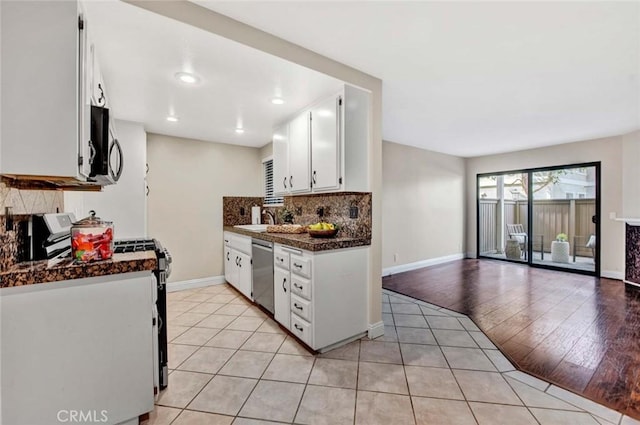 kitchen featuring stainless steel appliances, light tile patterned floors, tasteful backsplash, white cabinets, and sink