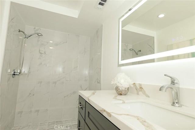 bathroom with vanity, tiled shower, and a skylight