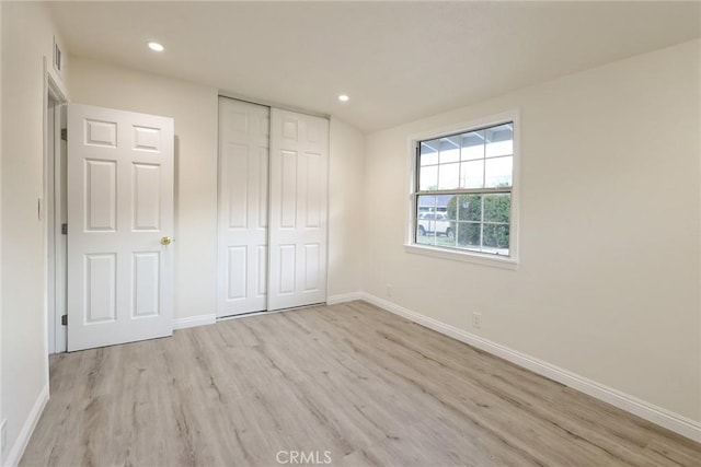 unfurnished bedroom featuring light wood-type flooring and a closet