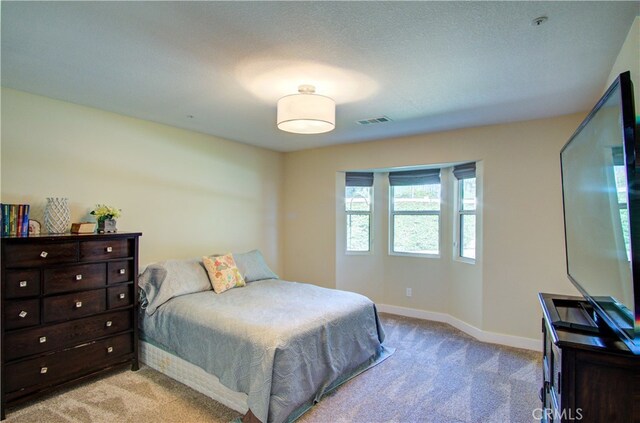 bedroom featuring light carpet and a textured ceiling