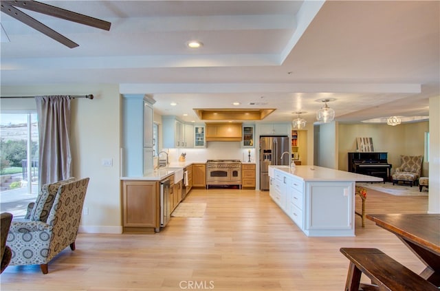 kitchen featuring a kitchen breakfast bar, ceiling fan, light hardwood / wood-style floors, stainless steel appliances, and a kitchen island with sink