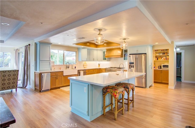 kitchen with a kitchen island, light hardwood / wood-style flooring, a breakfast bar, custom exhaust hood, and appliances with stainless steel finishes