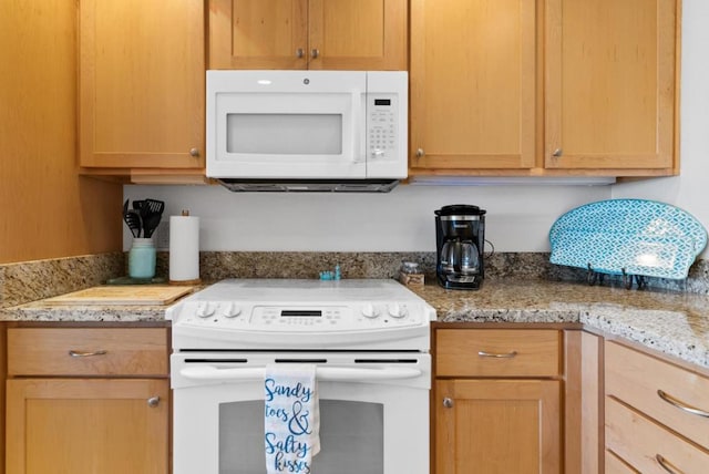 kitchen featuring light stone countertops and white appliances