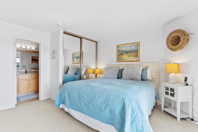 bedroom with a closet, sink, light carpet, and ensuite bath