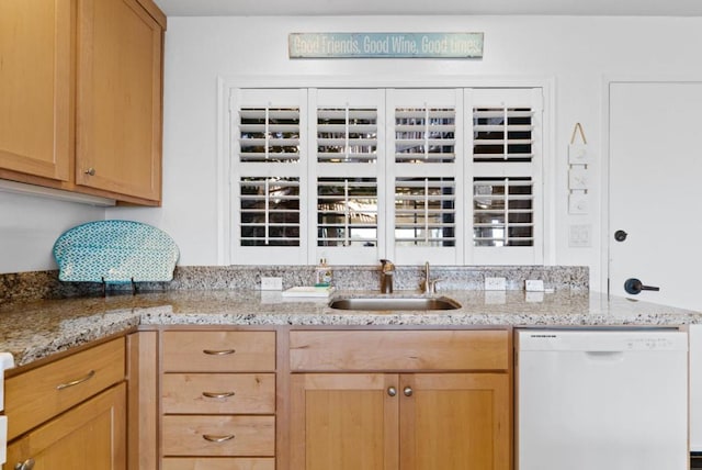 kitchen featuring light stone countertops, white dishwasher, and sink