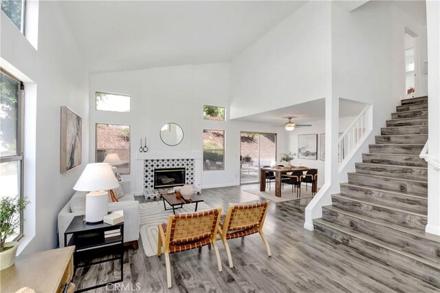 living room featuring hardwood / wood-style flooring, a towering ceiling, and a tiled fireplace