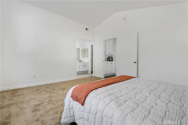 bedroom with lofted ceiling, connected bathroom, and light carpet