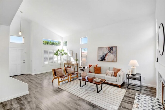 living room featuring a tiled fireplace, hardwood / wood-style flooring, and high vaulted ceiling