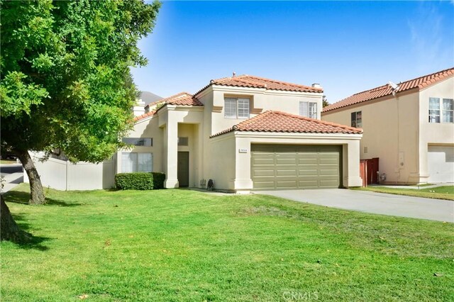 mediterranean / spanish-style home featuring a front yard and a garage