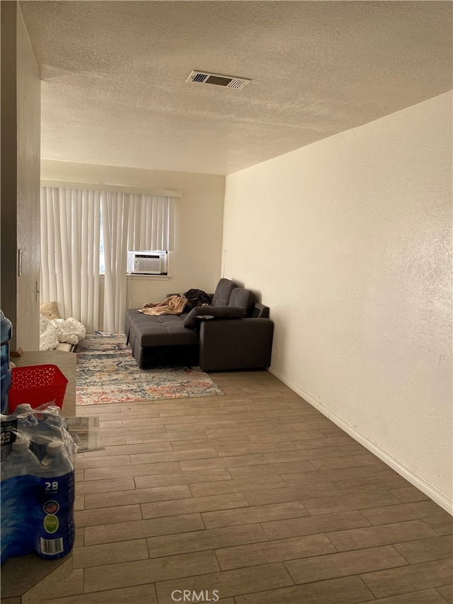 sitting room with cooling unit, a textured ceiling, and wood-type flooring