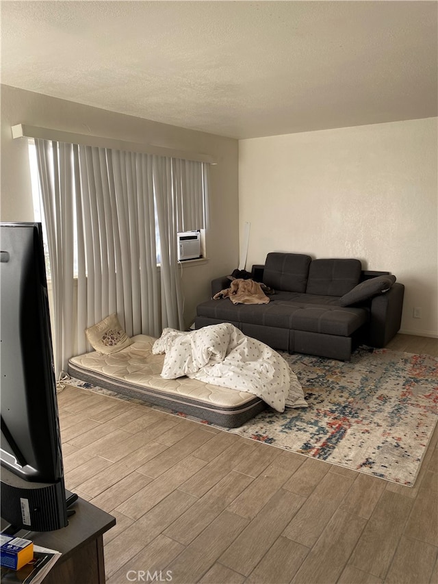 living room with cooling unit, a textured ceiling, and hardwood / wood-style flooring