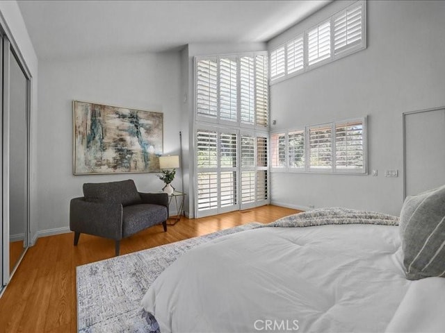 bedroom featuring baseboards, wood finished floors, and a towering ceiling