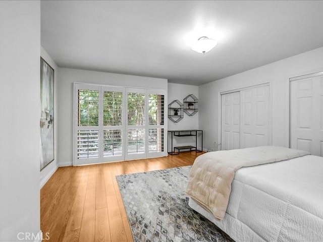 bedroom with multiple closets, wood finished floors, and baseboards