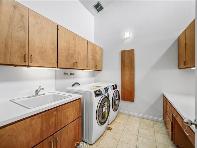 laundry area featuring a sink, light tile patterned flooring, cabinet space, and independent washer and dryer
