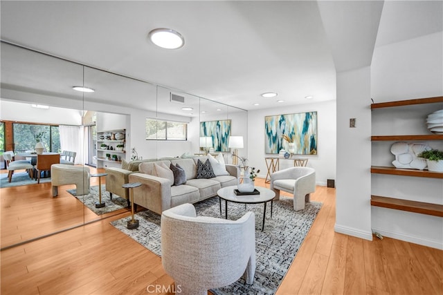 living room with baseboards, visible vents, wood finished floors, and recessed lighting