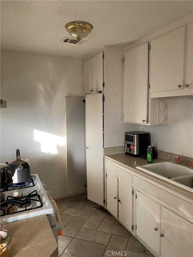 kitchen featuring sink, white cabinets, white gas range oven, and light tile patterned floors