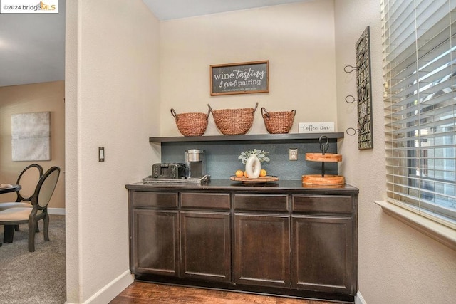 bar featuring dark brown cabinets, a wealth of natural light, and dark hardwood / wood-style flooring