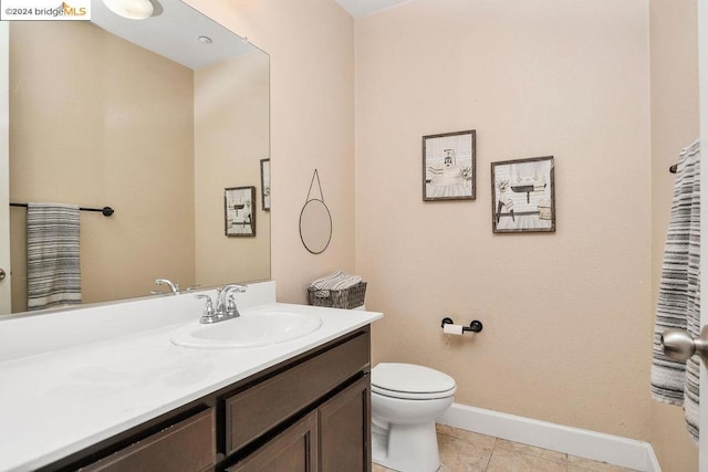 bathroom with toilet, vanity, and tile patterned floors