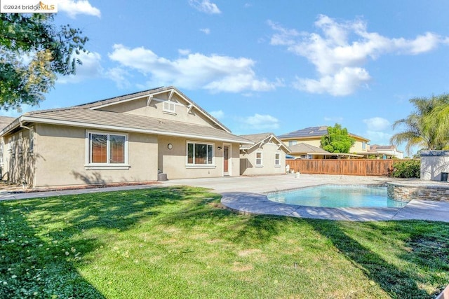 rear view of property with a patio, a fenced in pool, and a lawn