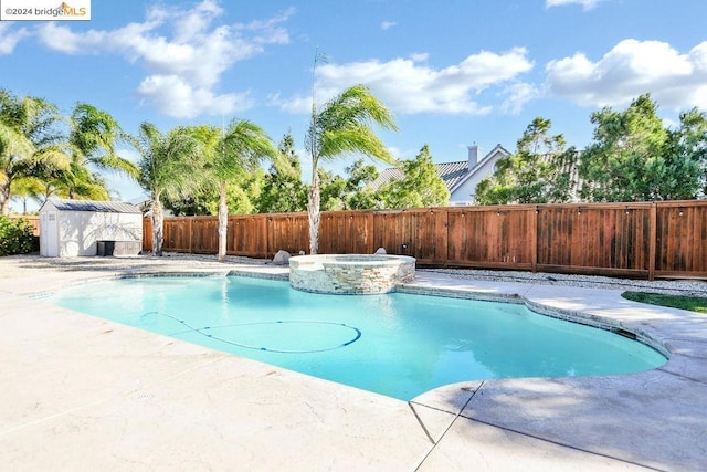 view of swimming pool with an in ground hot tub, a storage shed, and a patio