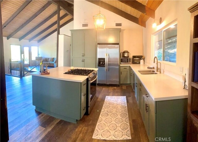 kitchen with dark wood-type flooring, sink, decorative light fixtures, appliances with stainless steel finishes, and beamed ceiling