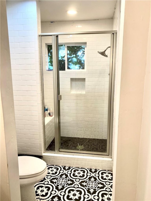 bathroom with tile patterned flooring, a shower with shower door, and toilet