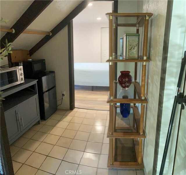 kitchen with appliances with stainless steel finishes, beam ceiling, gray cabinets, and light tile patterned floors