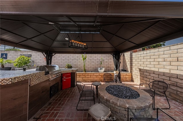 view of patio / terrace with a gazebo, a fire pit, exterior kitchen, and grilling area