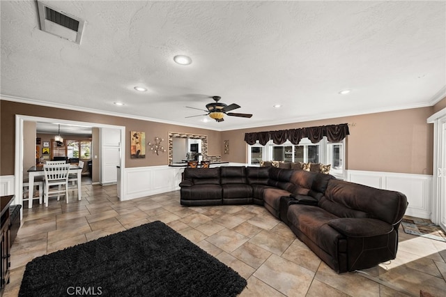 living room featuring ceiling fan, a textured ceiling, and ornamental molding