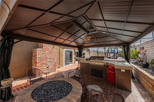 view of patio / terrace featuring a gazebo, exterior kitchen, an outdoor fire pit, and grilling area