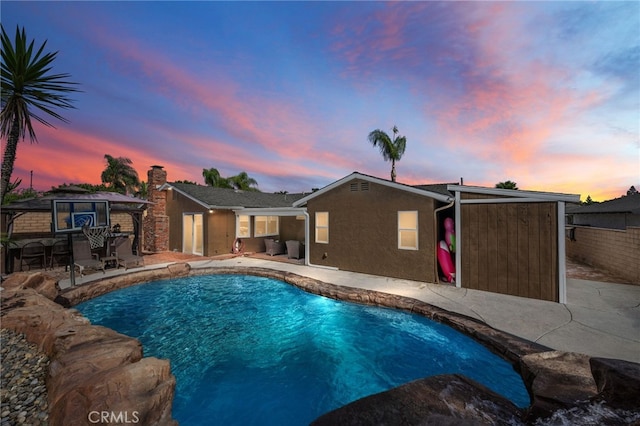 pool at dusk with a patio area