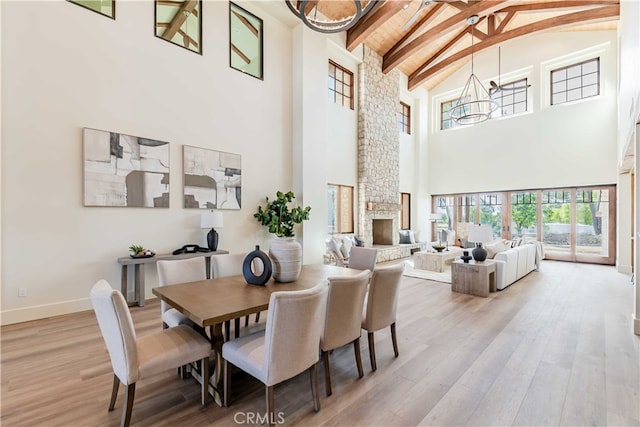 dining space featuring beamed ceiling, a fireplace, hardwood / wood-style flooring, and high vaulted ceiling