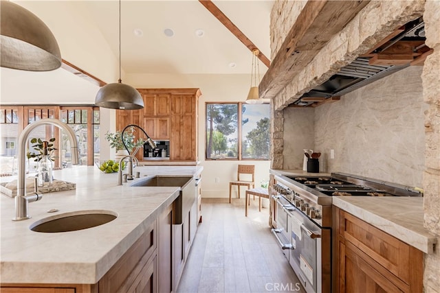 kitchen featuring tasteful backsplash, wood-type flooring, sink, range with two ovens, and decorative light fixtures