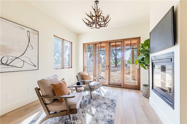 sitting room featuring light hardwood / wood-style floors, french doors, and an inviting chandelier