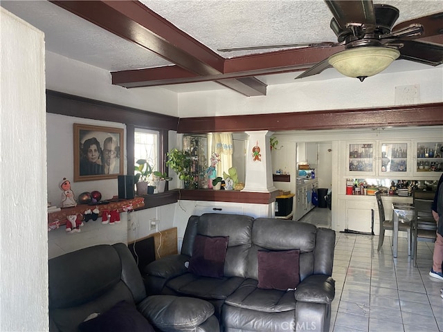 living room with ceiling fan, a textured ceiling, light tile patterned floors, and beamed ceiling